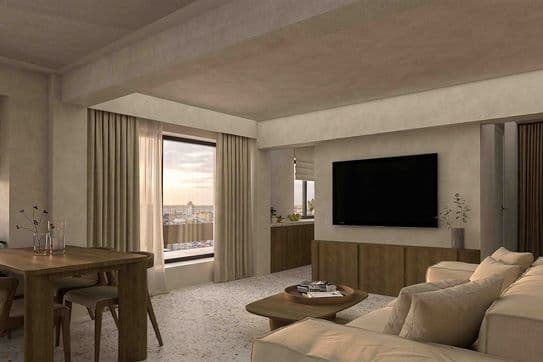 Minimalist beige living room with sectional sofa, wooden coffee and dining table, wall-mounted TV, and large curtained window overlooking city.