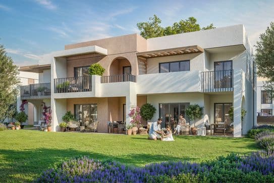 Modern two-story house with a garden, featuring people relaxing on the patio and garden chairs, surrounded by lush greenery and flowers.