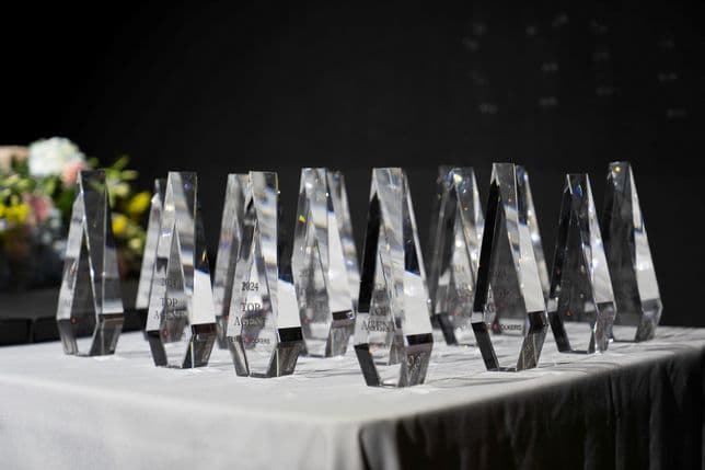 Several crystal awards are displayed on a table with a white tablecloth, against a dark background.