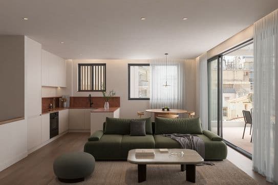 Modern open-plan living room with green sofa, round table, kitchenette, large windows, and balcony. Neutral tones and soft lighting create warmth.