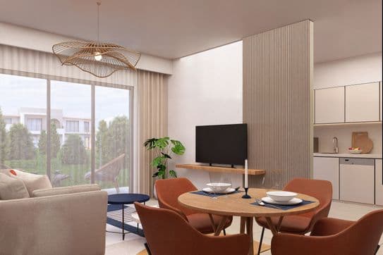 Modern open-plan living room with a round dining table, brown chairs, cozy seating, TV, and large window showing greenery outside.