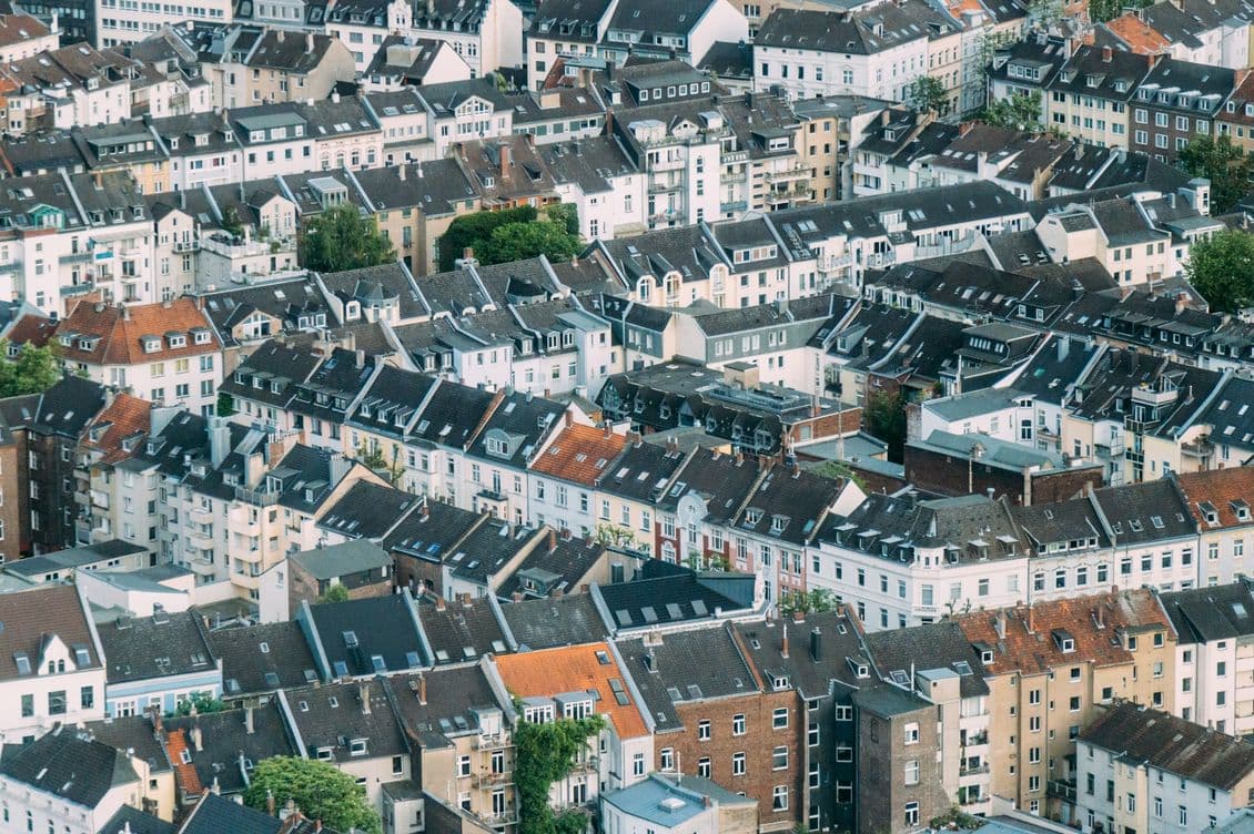 Aerial view of densely packed European townhouses with varied rooftops and a mix of modern and traditional architecture.