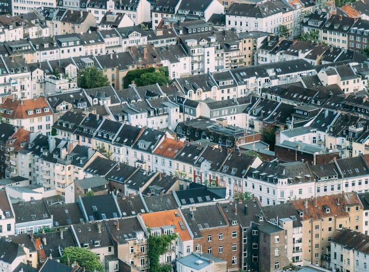 Aerial view of densely packed European townhouses with varied rooftops and a mix of modern and traditional architecture.
