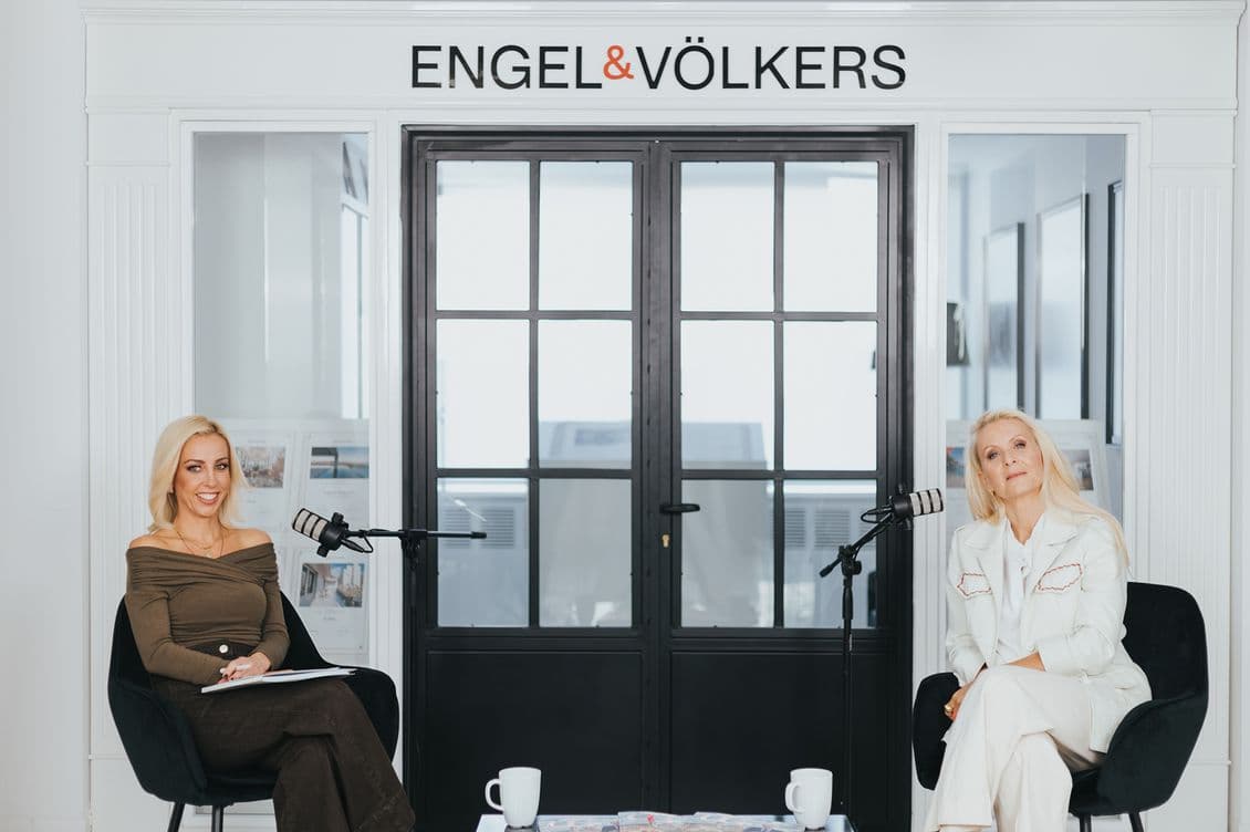 Δύο γυναίκες, η Κατερίνα Γκαγκάκη και η Λίλη Πυράκη, κάθονται σε μαύρες καρέκλες με μικρόφωνα ανάμεσά τους μπροστά σε μια γυάλινη πόρτα με μαύρο πλαίσιο. Η επιγραφή από πάνω γράφει ENGEL &amp; VÖLKERS, καθώς αντικρίζουν ο ένας τον άλλον, ο ένας κρατώντας ένα σημειωματάριο.