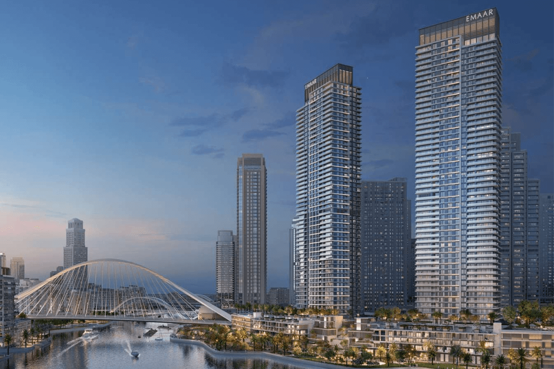 Skyline view of modern skyscrapers by a waterfront at dusk, featuring a distinctive arched bridge and illuminated buildings.