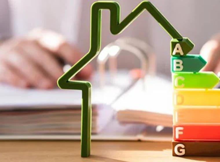 House with energy efficiency classes from A to G, person working at a desk, symbolizing sustainable real estate