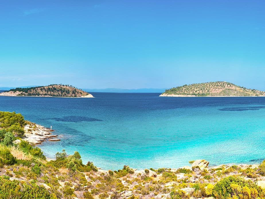 Scenic view of turquoise sea, islands, and lush green vegetation under a clear blue sky.