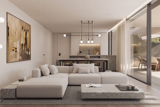 Bright modern open-plan living room with low beige sectional, stone coffee table, kitchen island with pendant lights and sliding glass doors to patio.