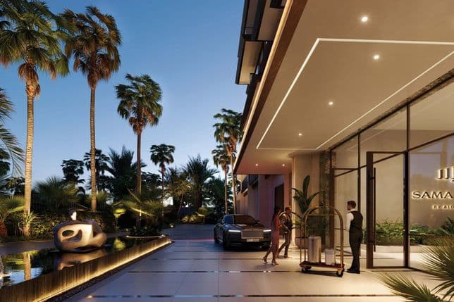 Elegant hotel entrance at dusk with palm trees, a fountain, and a luxury car. A doorman assists guests near the glass doors.