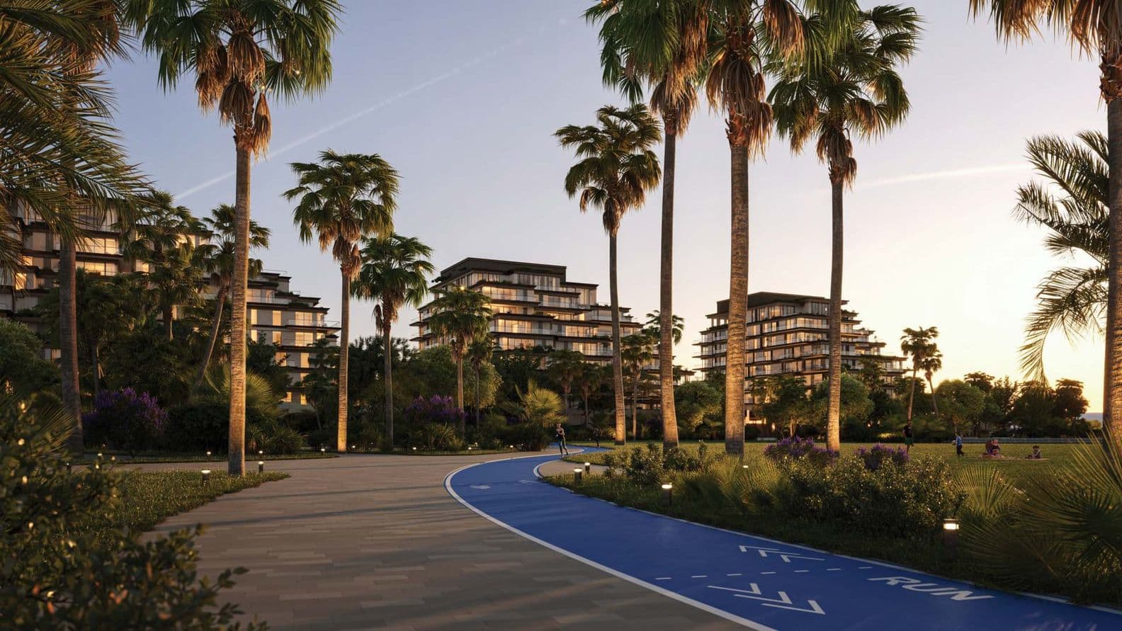 Pathway lined with palm trees, adjacent to modern buildings at sunset. A blue running track is visible on the right.