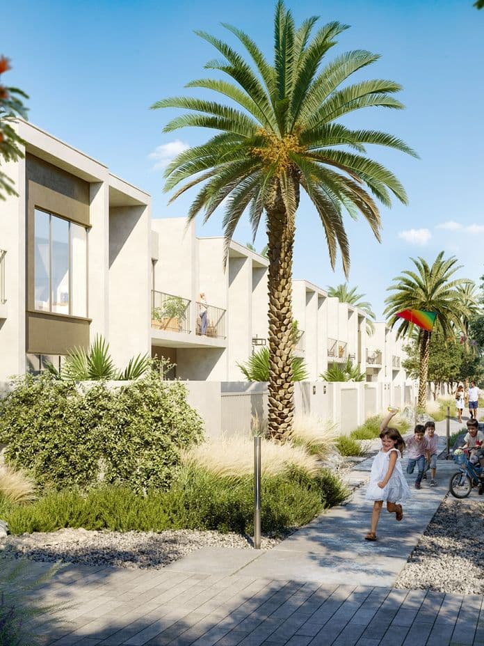 Modern residential area with palm trees, people jogging and children playing on a sunny day. Balconies overlook landscaped pathways.