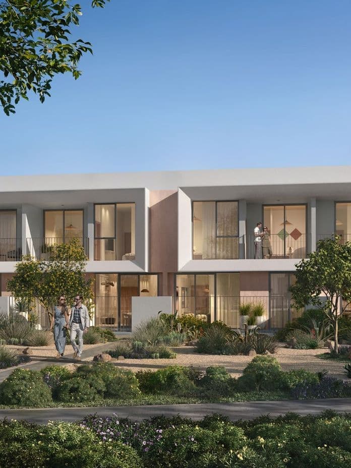 Modern two-story apartment complex with large windows, surrounded by greenery. People walking and children playing in the foreground.
