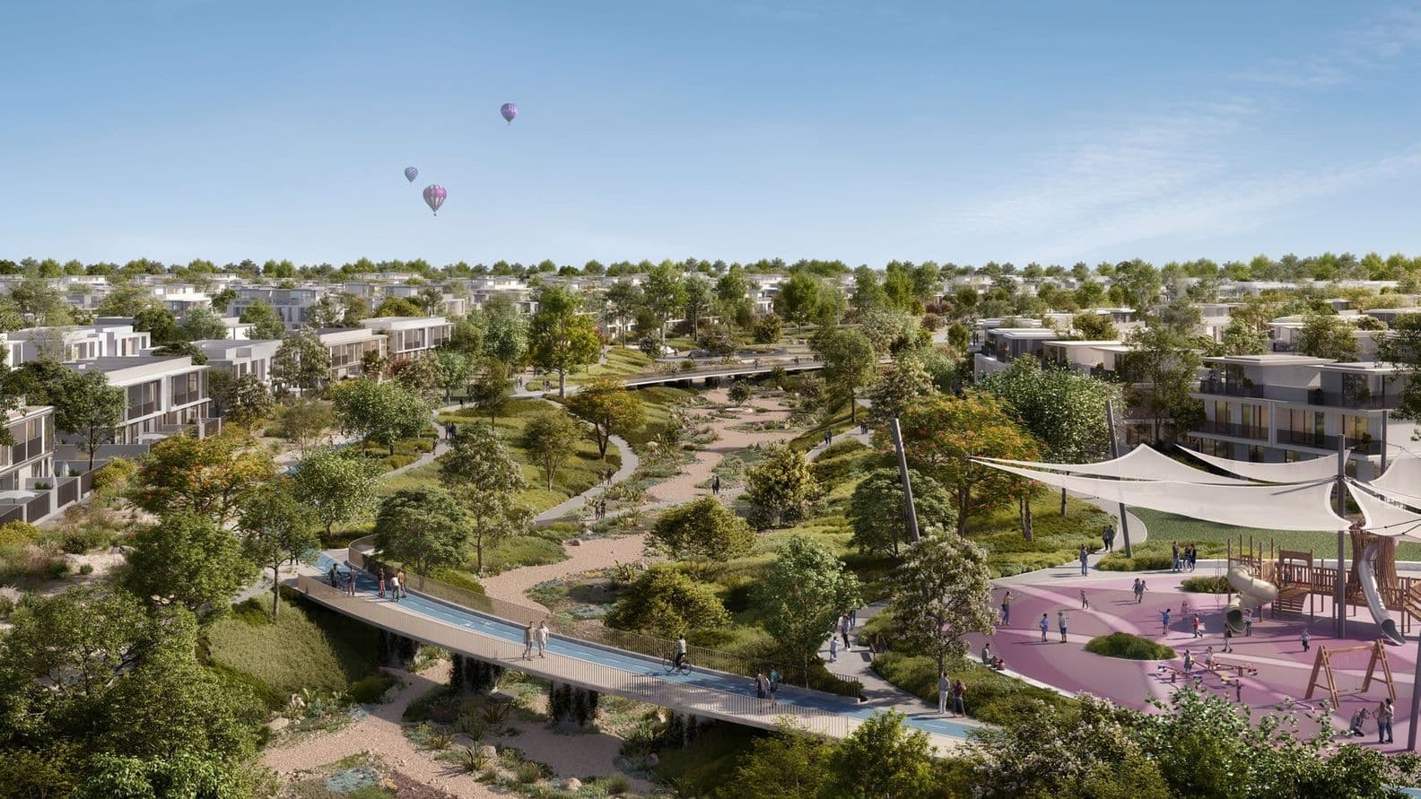 Scenic residential area with modern houses, lush greenery, a playground, walking paths, and hot air balloons in the clear blue sky.