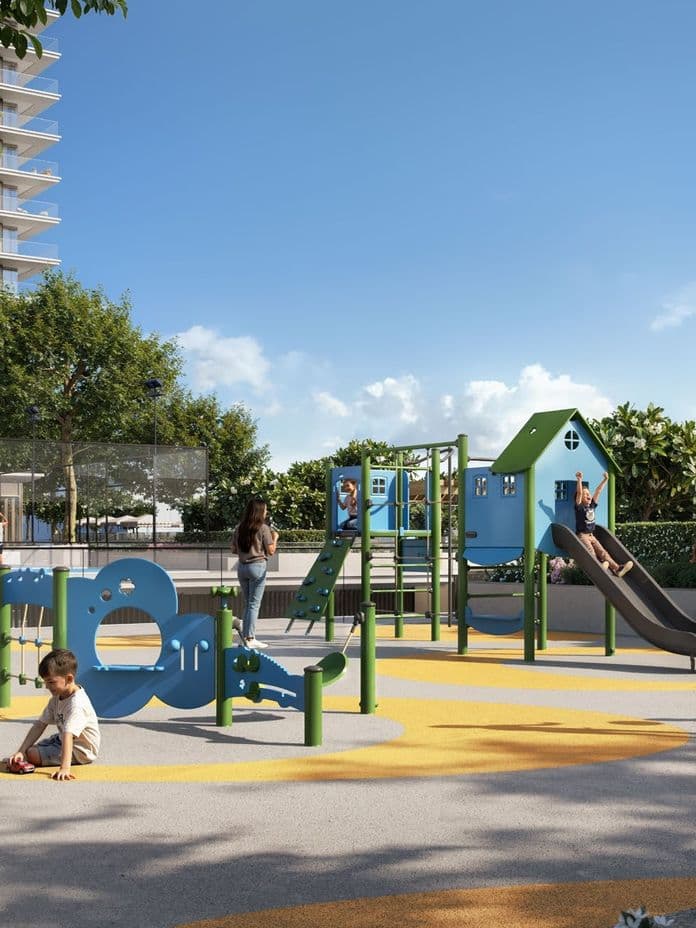 Colorful playground with slides, climbing frames, and shaded seating surrounded by greenery.