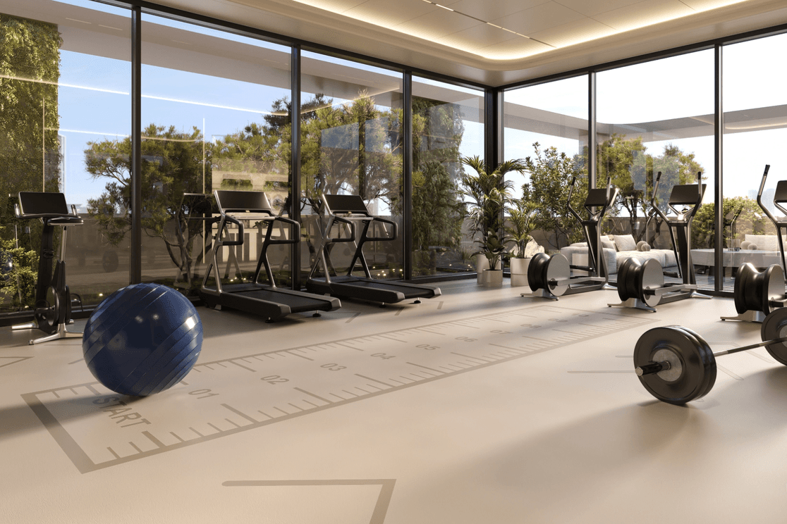 Indoor gym at Coventry Living in Jumeirah Village Circle featuring modern fitness equipment and floor-to-ceiling windows.
