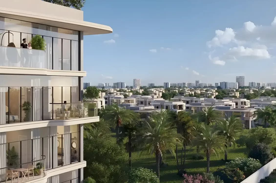 Modern apartment building overlooking a lush green landscape with trees, gardens, and distant city skyline under a clear blue sky.