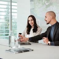 Immobilienmakler berät Eigentümer zum Verkaufszeitpunkt 2025 im modernen Büro mit Laptop und Stadtkarte