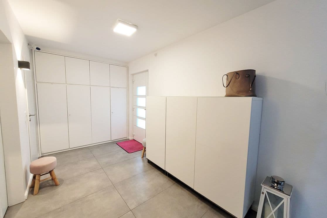 Bright and renovated hallway with large white cabinets, minimalist decor and tiled floor