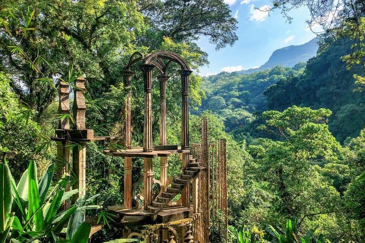 A surreal garden with lush jungle, enchanted sculptures and mystical concrete structures in Las Pozas, Mexico.