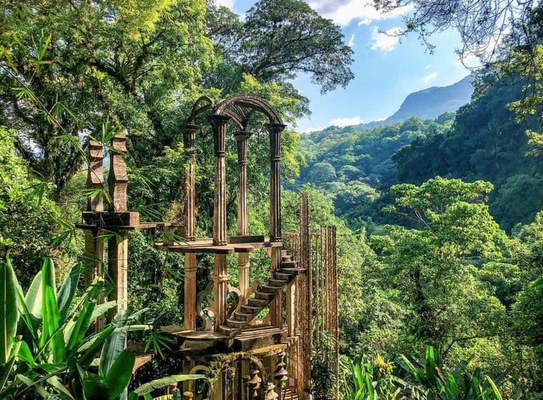A surreal garden with lush jungle, enchanted sculptures and mystical concrete structures in Las Pozas, Mexico.