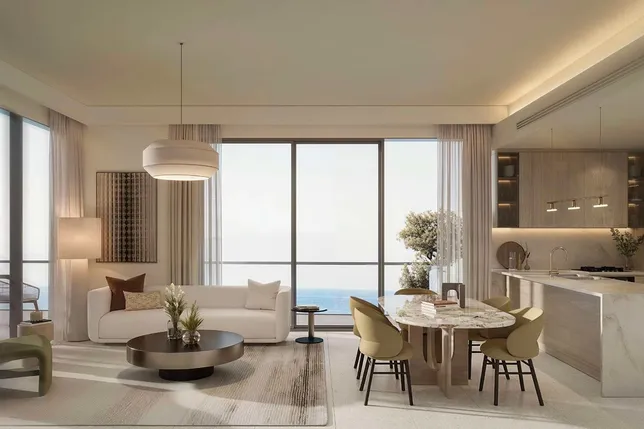 Bright open-plan living area with a marble kitchen island, round coffee table, cream sofa, and floor-to-ceiling windows overlooking the sea. KI-generiertes Bild