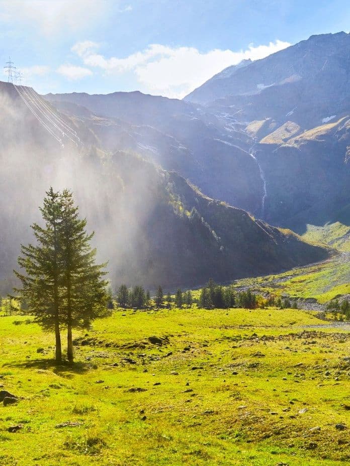Hollersbach Naturaufnahme mit grünen Wiesen, Bergen und Wasserfall.