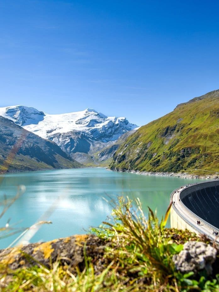 Reservoir in Kaprun with views of snow-covered mountains and blue sky.