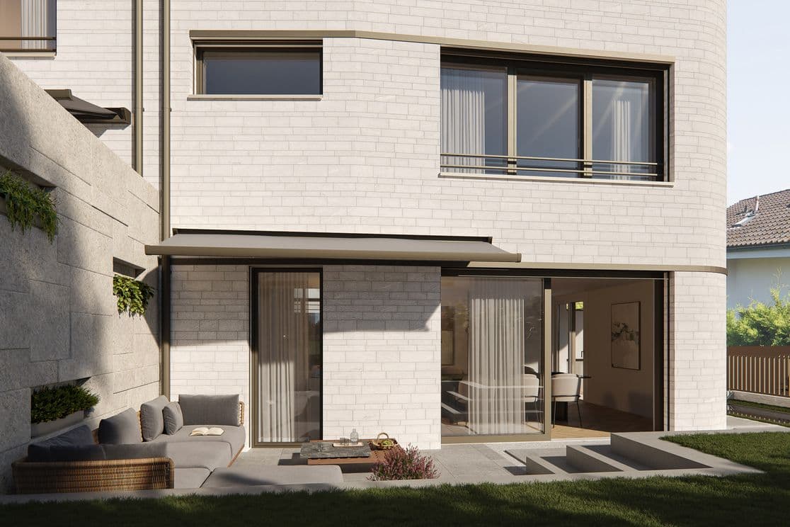 Modernes Haus mit großen Fenstern, Glasschiebetüren, Terrasse, Ecksofa und einem kleinen Tisch mit Dekoration, umgeben von einem Rasen.