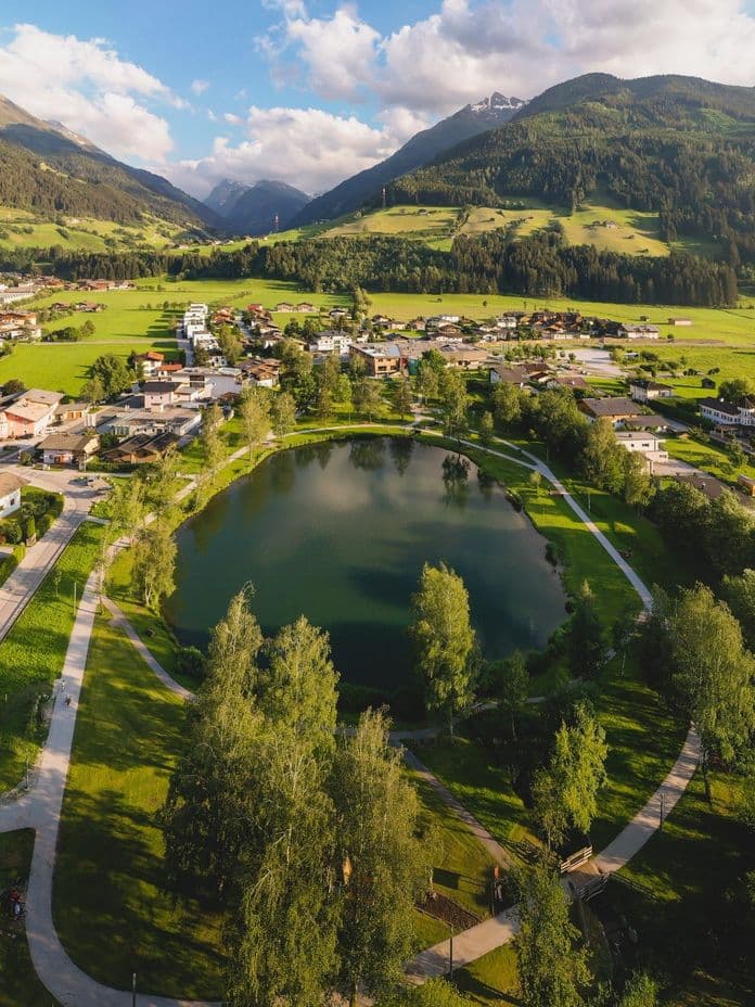 Luftaufnahme des Zierteichs in Mittersill mit grüner Umgebung.