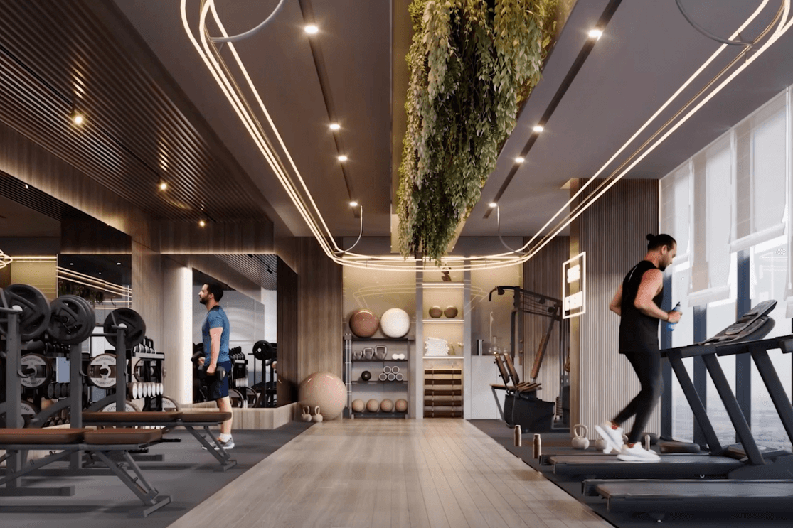 Indoor gym at Voxa featuring treadmills facing large windows, strength training equipment, mirrored walls, and overhead lighting with suspended greenery.