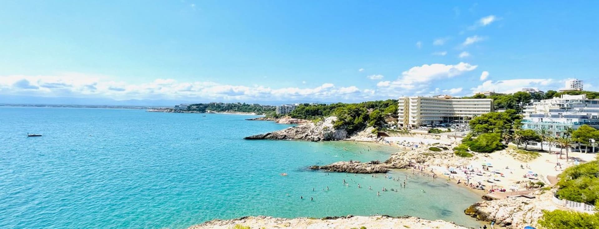 Costa Dorada beach image, photographed by Engel Volkers team. Turquoise water and some buildings.