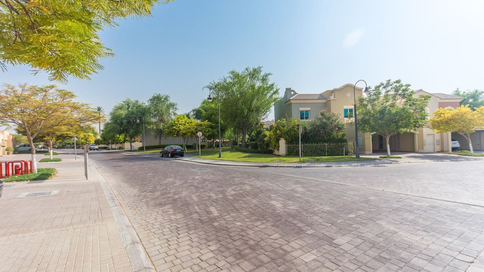 Row of contemporary townhouses in Victory Heights with shaded parking, landscaped walkways, and Dubai skyline in the background.