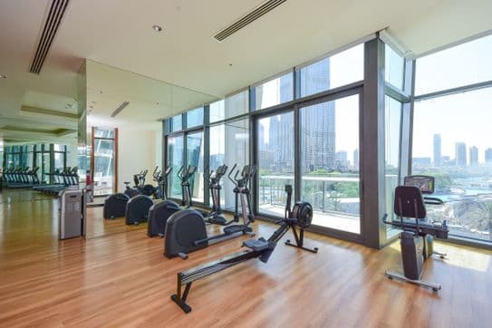 Modern gym at Burj Vista in Dubai with weight racks, fitness machines, mirrored walls, and large windows allowing in natural light.