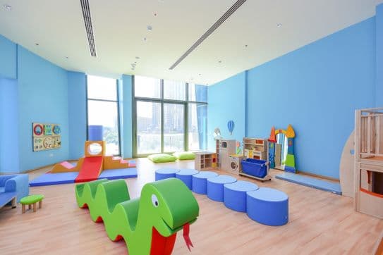 Children’s playroom at Burj Vista in Dubai with colorful play equipment, padded flooring, and large windows with city views.