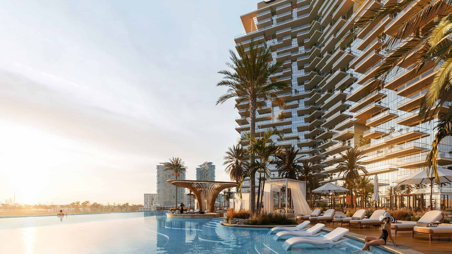 Luxurious rooftop pool with lounges, palm trees, and modern building at sunset, offering a serene and elegant atmosphere.