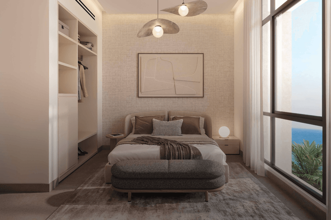Modern bedroom interior at Playa Viva with built in storage, neutral finishes, and a large window overlooking the Al Marjan Island waterfront.