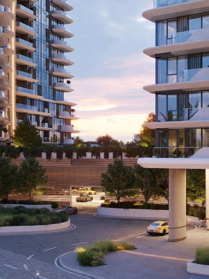 Modern high-rise buildings with curved balconies at sunset; landscaped greenery and parked cars in the foreground.