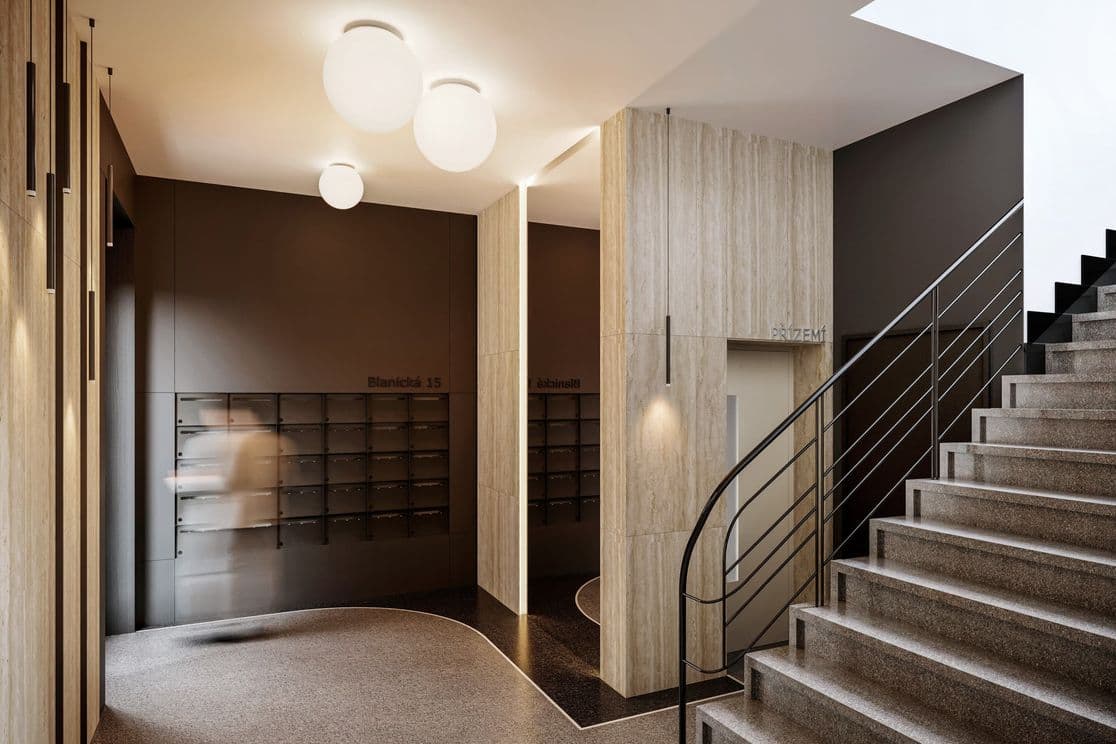 Modern entrance area of a residential building with dark mailboxes, backlit wood paneling, stone flooring, round ceiling lights, and a staircase with metal railing.