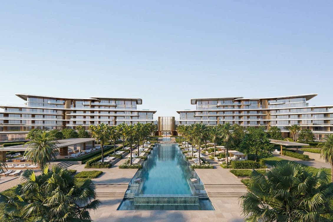 Luxurious resort with modern architecture, surrounded by palm trees and an expansive central pool under a clear blue sky.