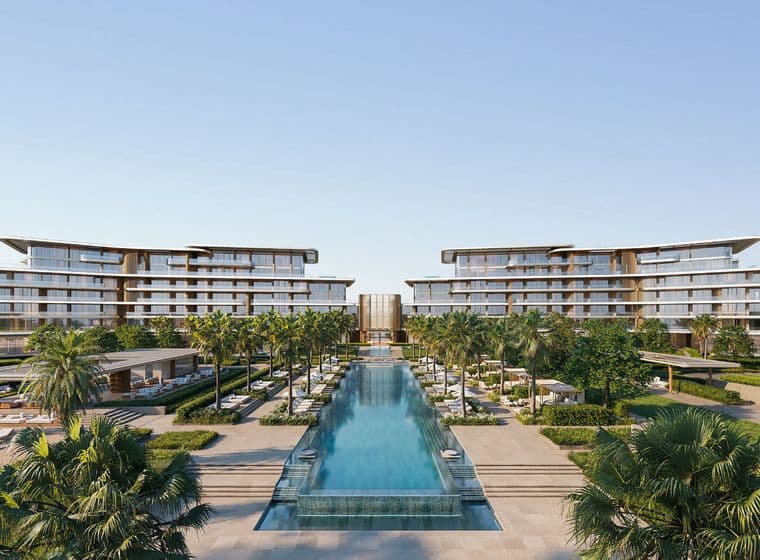 Luxurious resort with modern architecture, surrounded by palm trees and an expansive central pool under a clear blue sky.