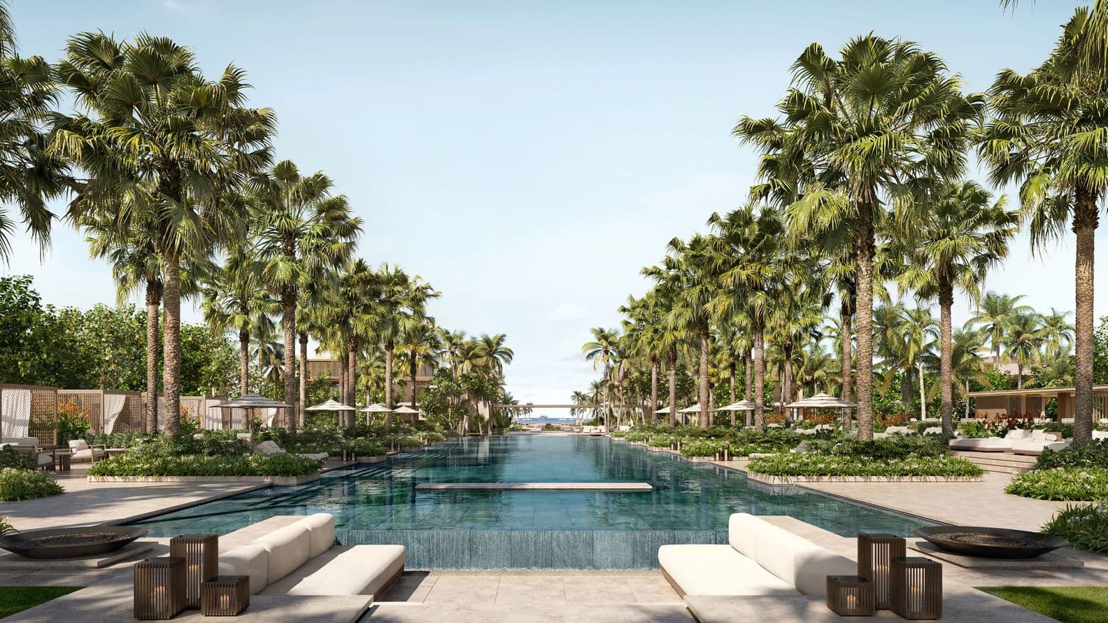 A luxurious outdoor pool surrounded by palm trees, with sun loungers and parasols on a sunny day.