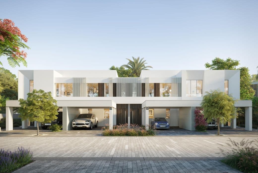 Modern white townhouse with large windows, two garages, and surrounded by lush greenery and palm trees under a clear blue sky.
