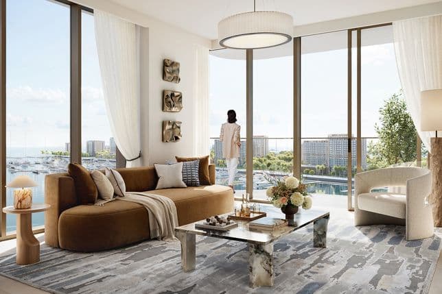 Spacious, modern living room with floor-to-ceiling windows overlooking Rashid Marina, featuring a brown curved sofa, marble coffee table, and a woman enjoying the panoramic sea view.