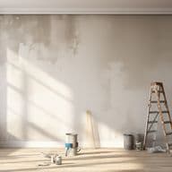 Ein sonnendurchfluteter Raum mit einer Holzleiter, Farbdosen, Pinseln und Tüchern auf einem hellen Holzfußboden, neben einem großen Fenster.