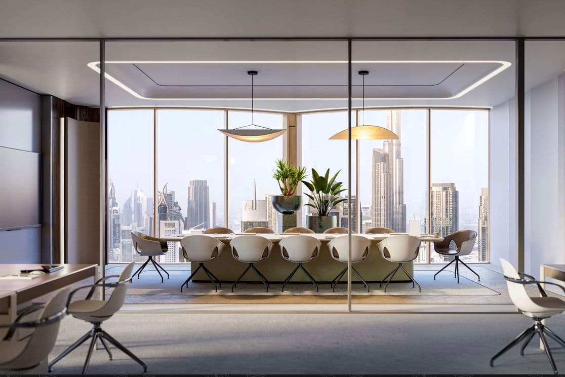Modern conference room with a long table, chairs, and plants, overlooking a city skyline through large windows.