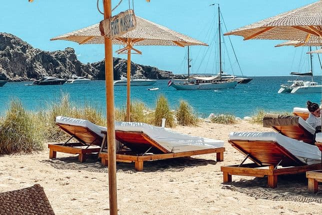Ruhige Strandszene mit ordentlich aufgereihten Sonnenliegen unter der Sonne – ideal zum Entspannen an der klaren Mittelmeerküste.