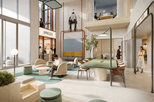 Bright modern lobby with tall windows, mint seating, a long green table, and people chatting; upper level shows a group at a desk.