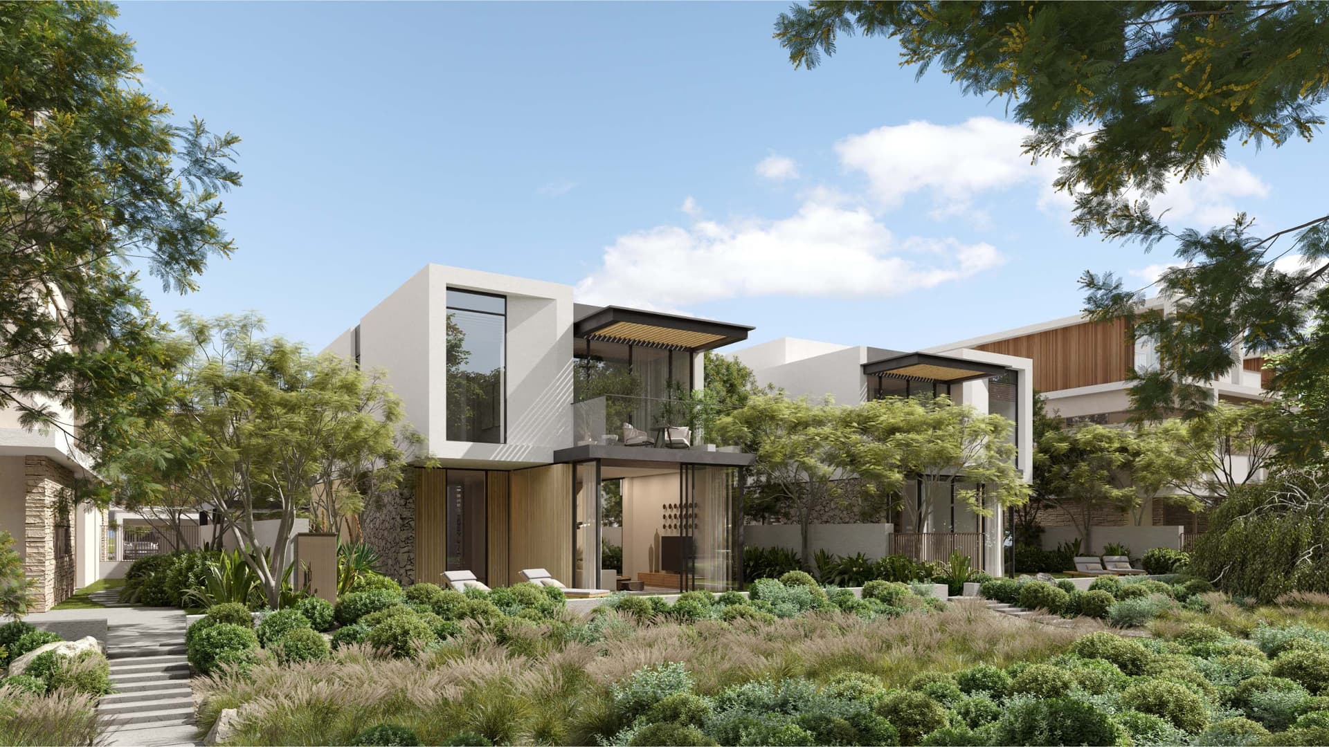 Modernes weißes zweistöckiges Haus mit einem Balkon und einem üppigen grünen Rasen an einem sonnigen Tag.