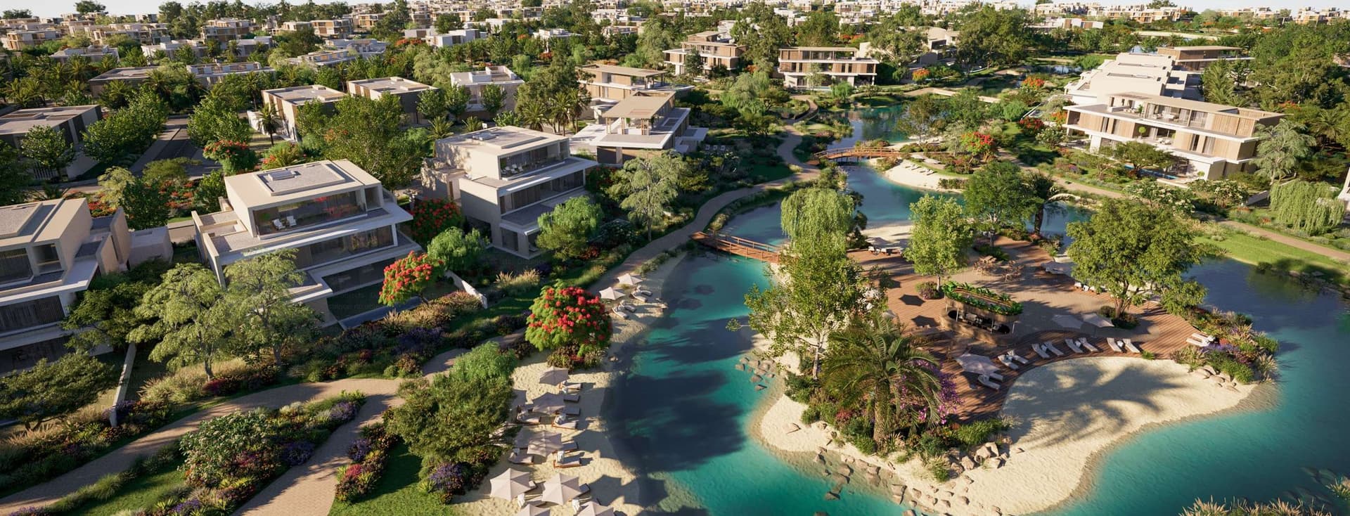 Luftaufnahme einer luxuriösen Immobilienentwicklung mit modernen Häusern, einer türkisfarbenen Lagune und üppiger grüner Landschaftsgestaltung.