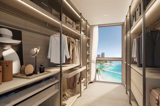 Luxuriöser begehbarer Kleiderschrank mit ordentlich angeordneter Kleidung und Accessoires sowie einem großen Fenster mit atemberaubendem Meerblick.